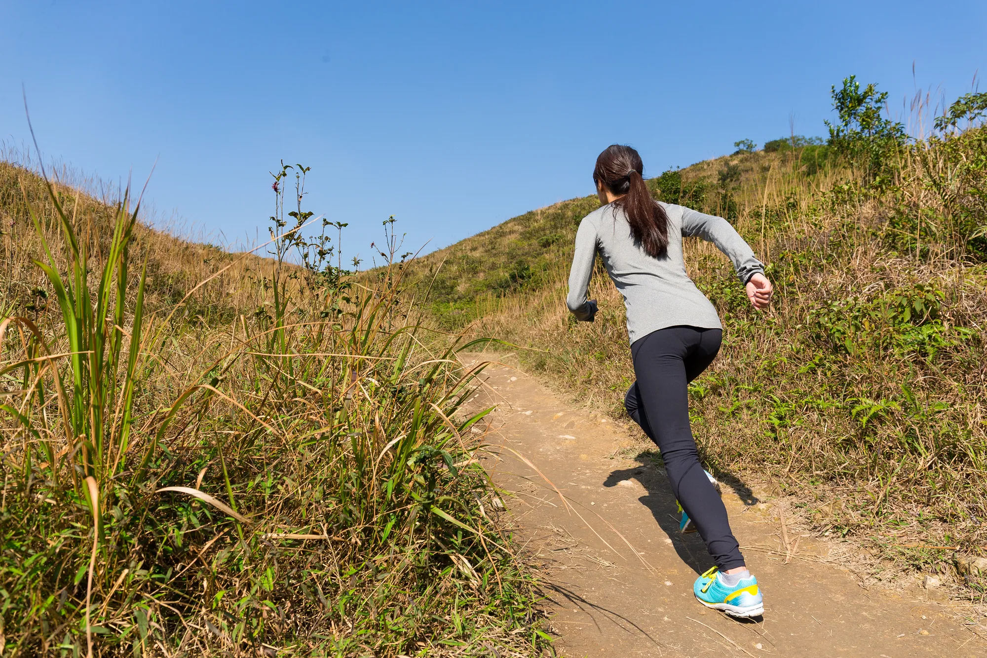Mujer atlética corriendo en montaña — entrenamiento esencial