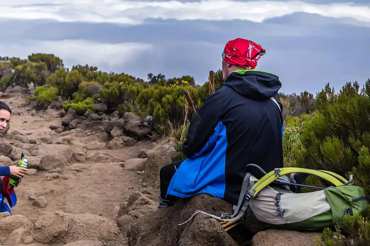 Ein Wanderer rastet auf einem hochgelegenen Bergpfad