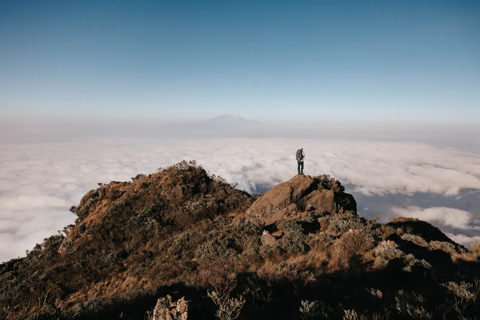 A trekker high on the mountain above a sea of clouds