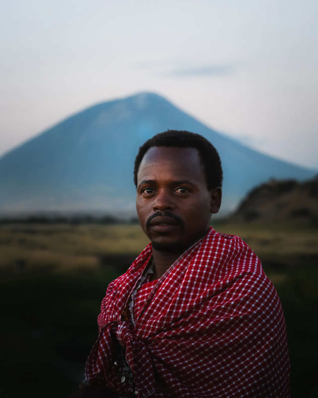 Um homem massai de shuka vermelha sob o Ol Doinyo Lengai