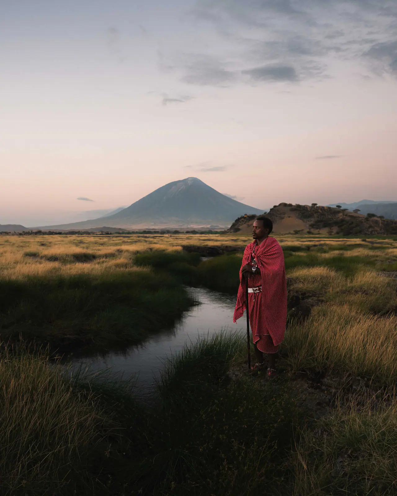 A Maasai man in a red shuka beneath Ol Doinyo Lengai