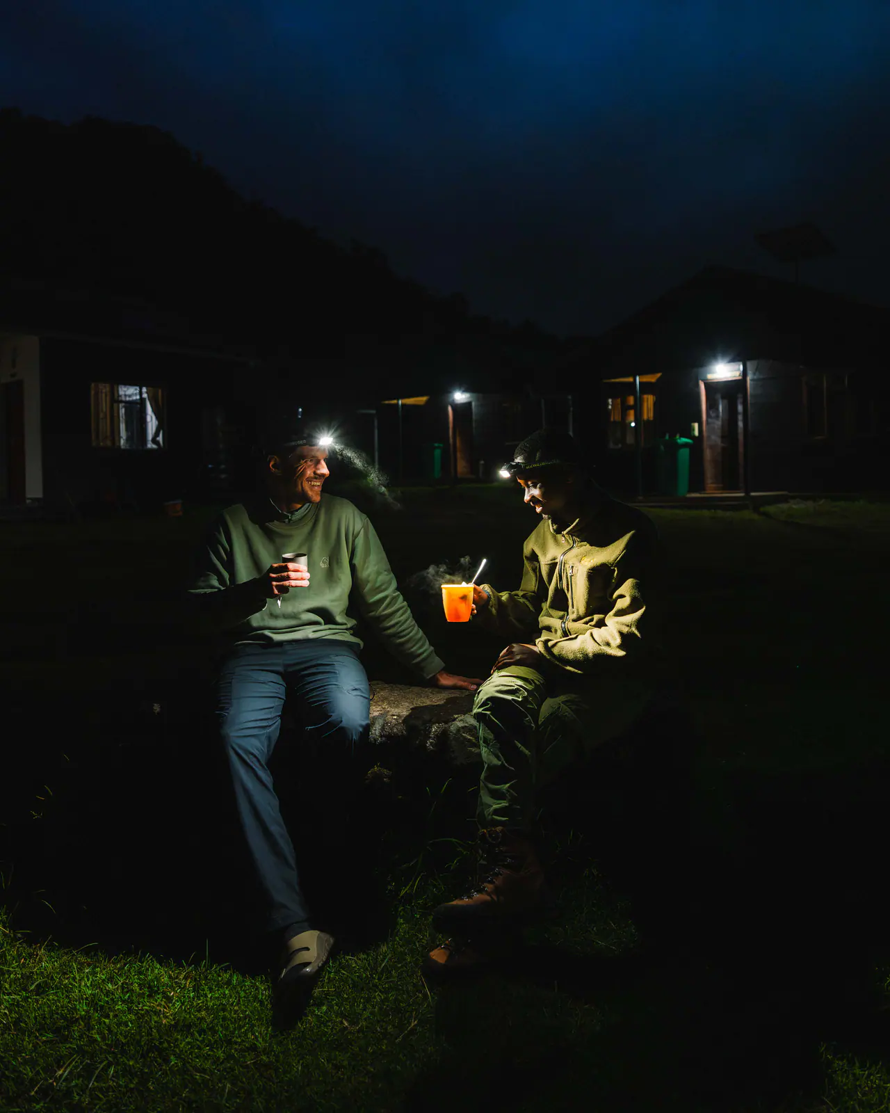 Guides sharing tea by headlamp at camp