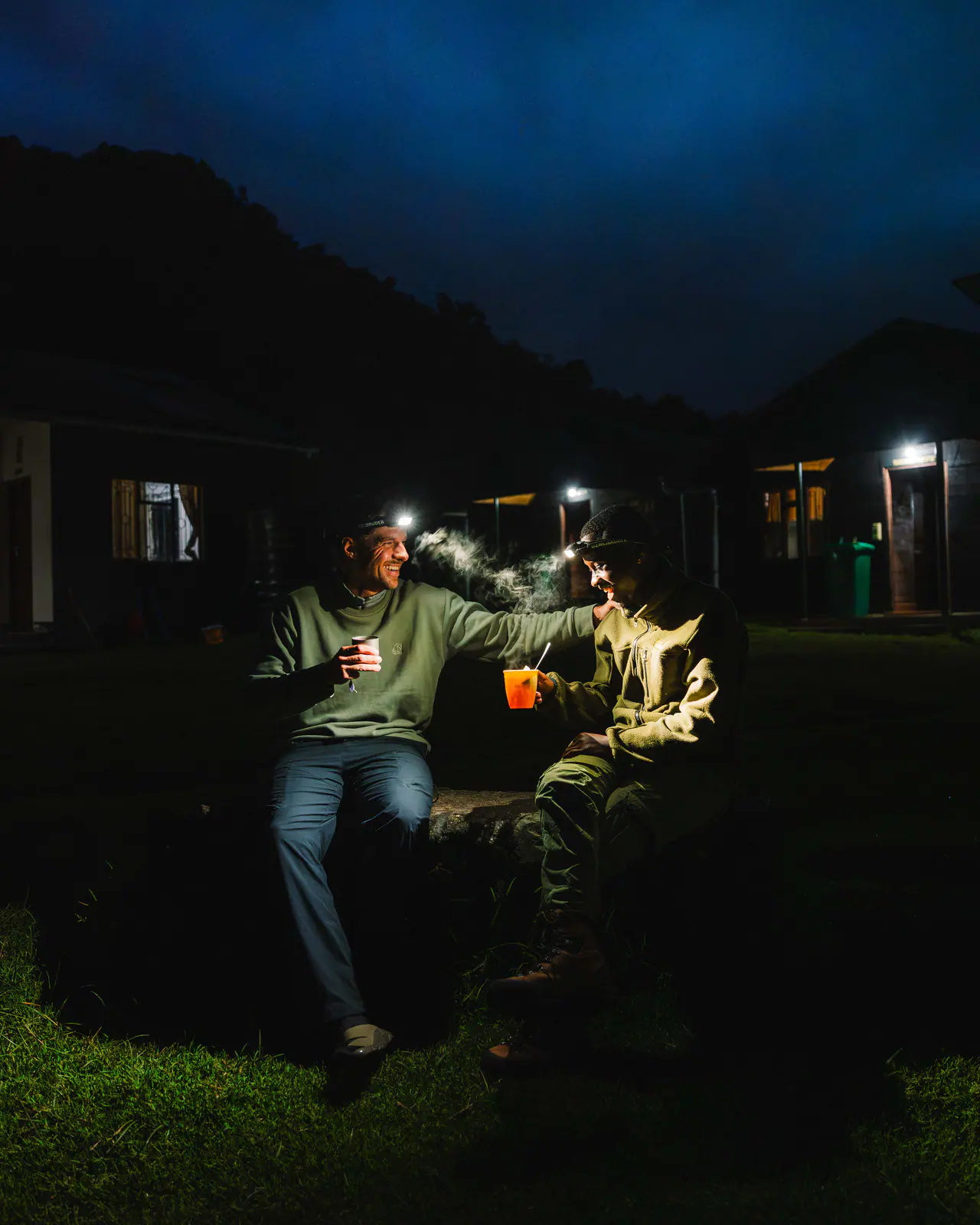 Guides sharing tea by headlamp at camp