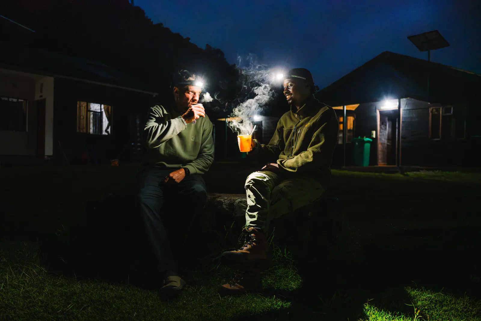 Guides sharing tea by headlamp at camp