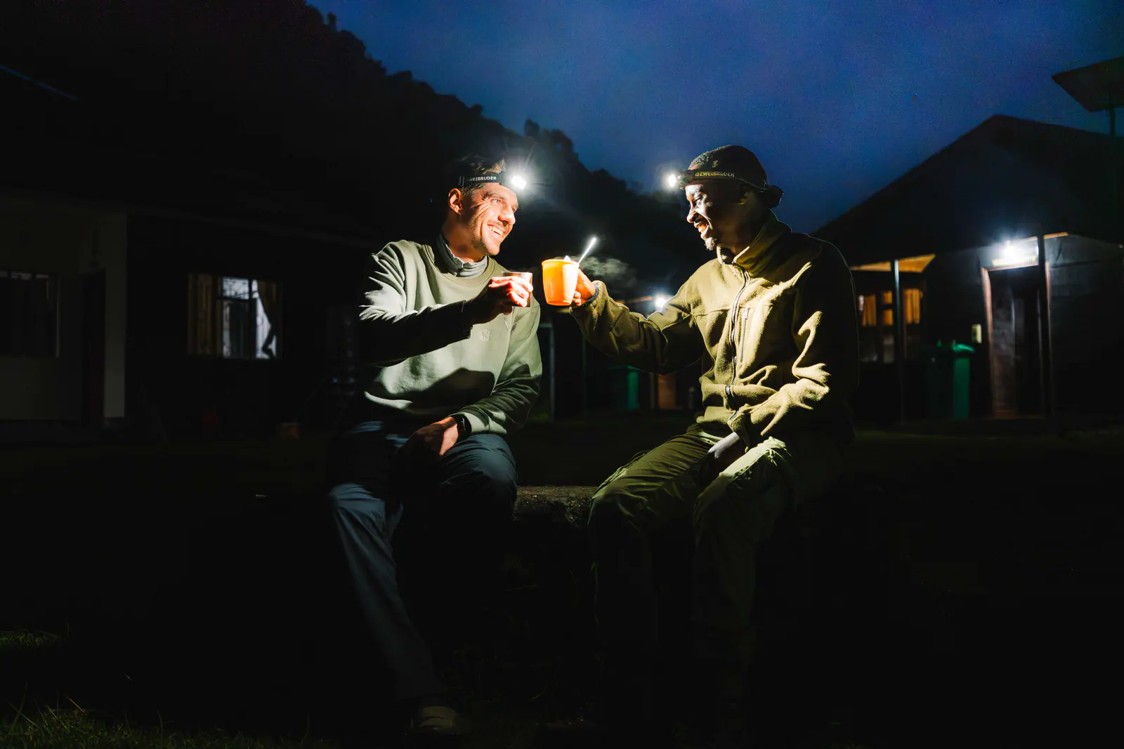Guides sharing tea by headlamp at camp