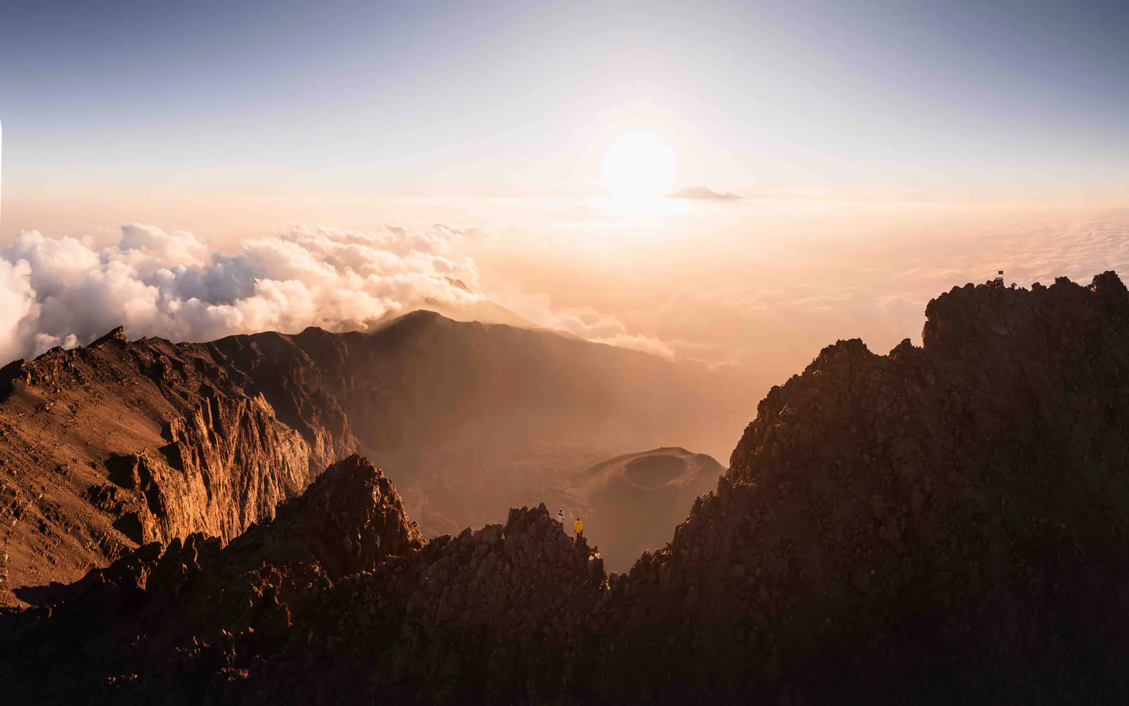A lone trekker on a jagged ridge at sunrise