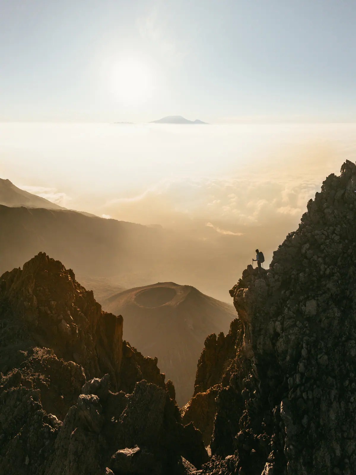 A lone trekker on a jagged ridge at sunrise