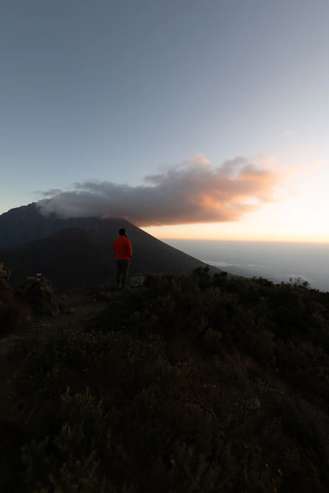 Un excursionista descansando en una cresta al amanecer