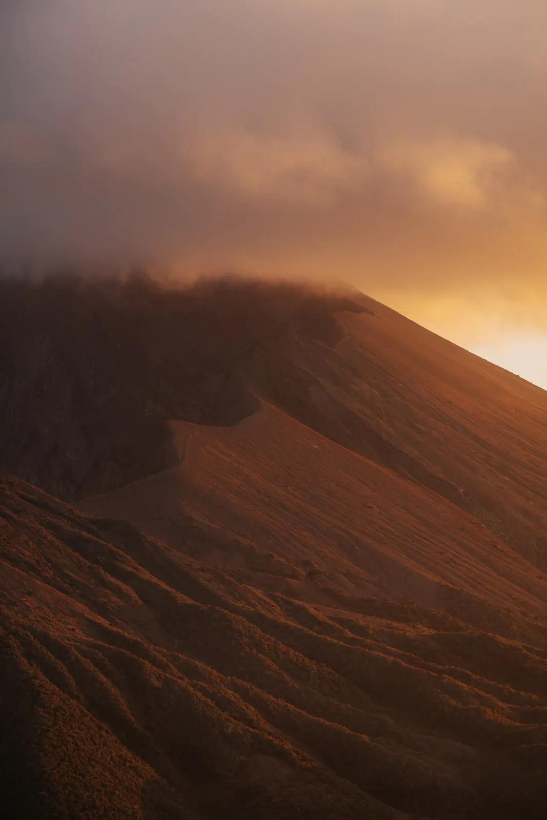 Golden light over a volcanic summit above the clouds