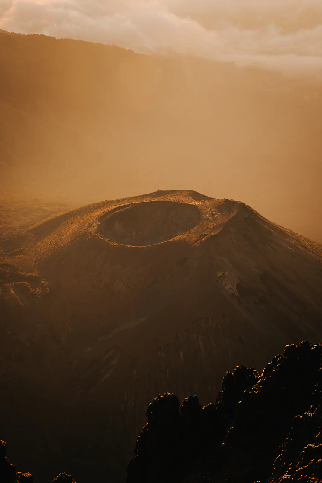 Golden light over a volcanic summit above the clouds