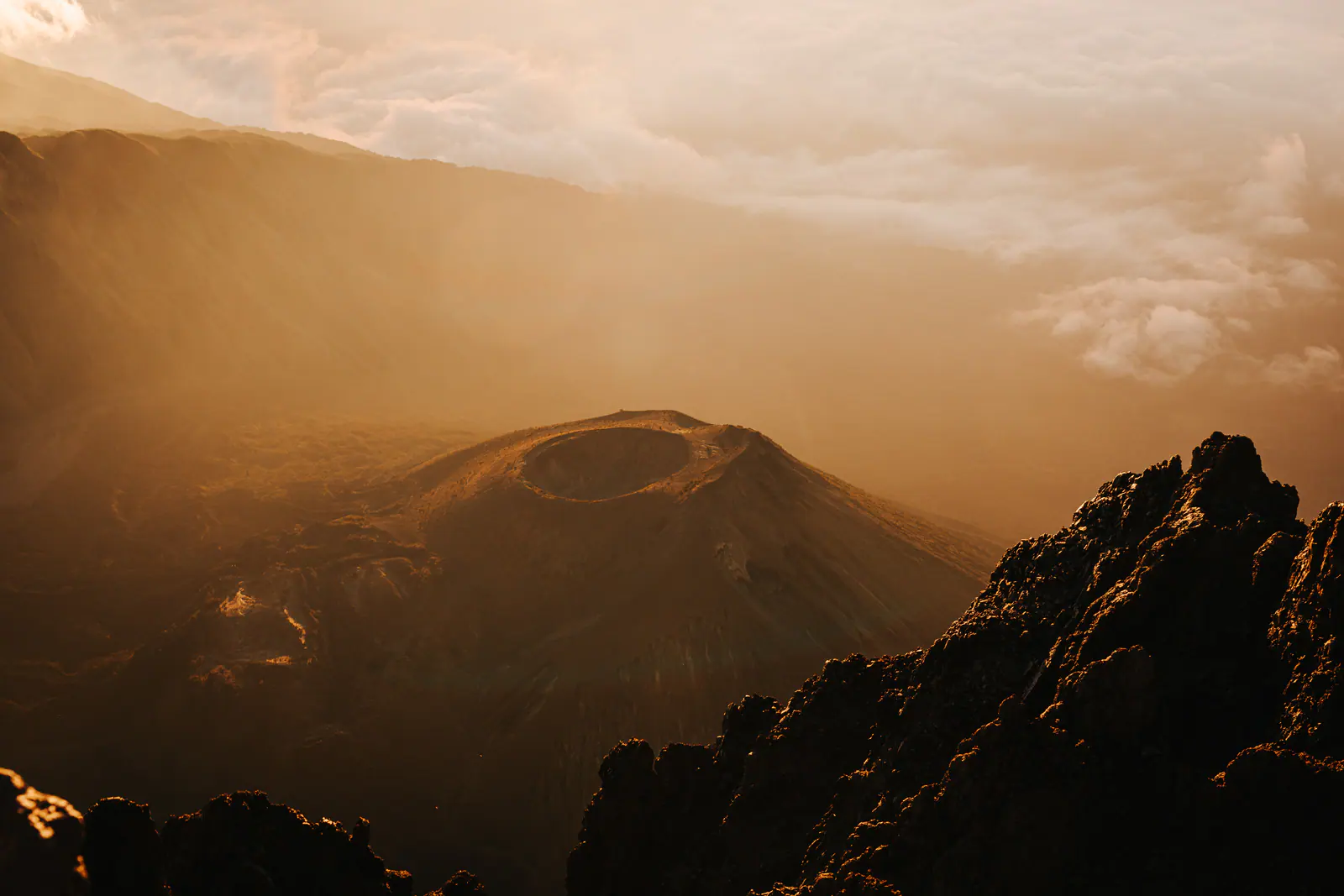 Golden light over a volcanic summit above the clouds