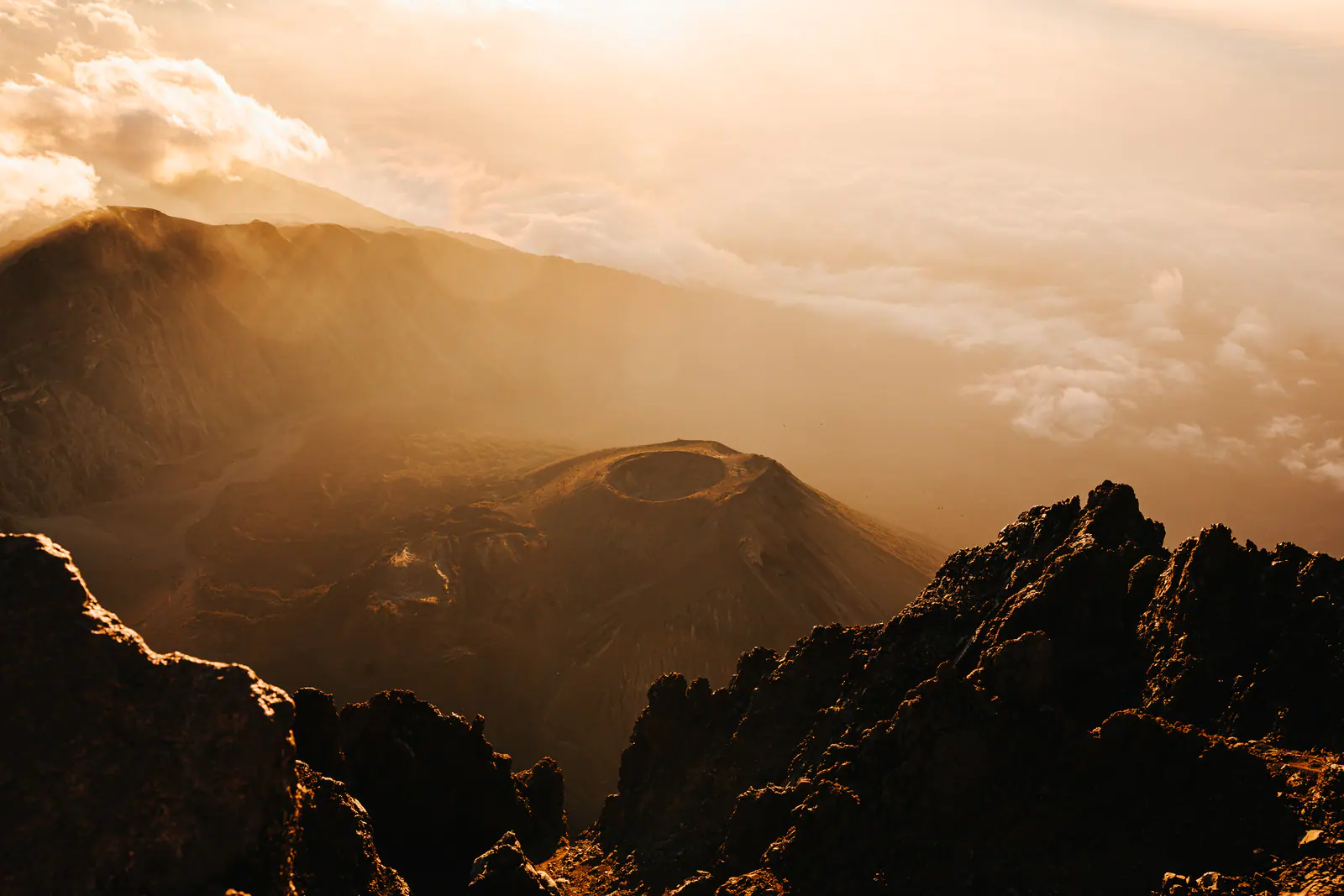 Golden light over a volcanic summit above the clouds