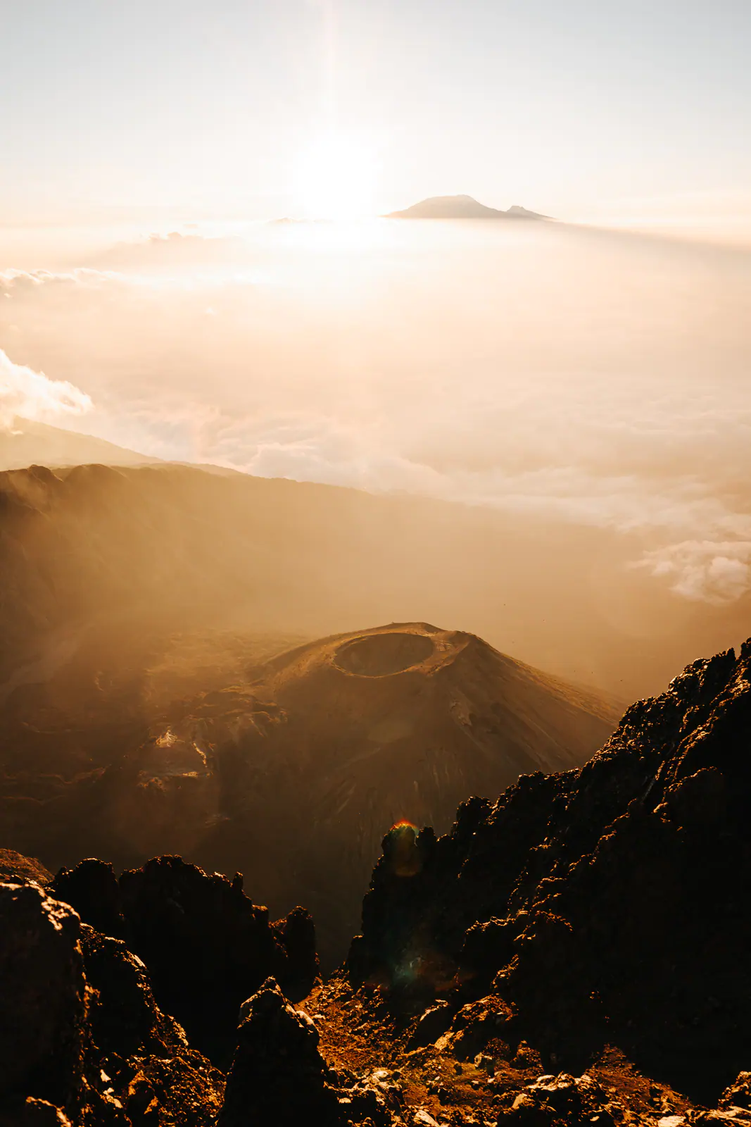 Golden light over a volcanic summit above the clouds