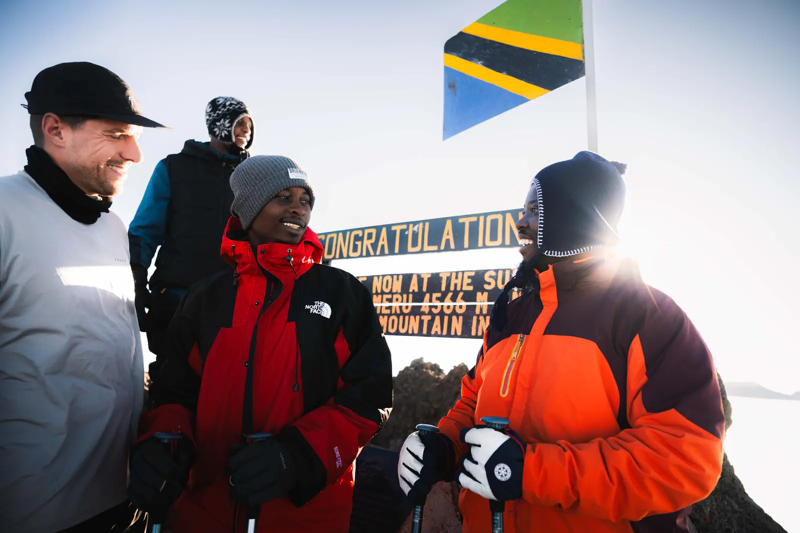Climbers celebrating at the summit sign