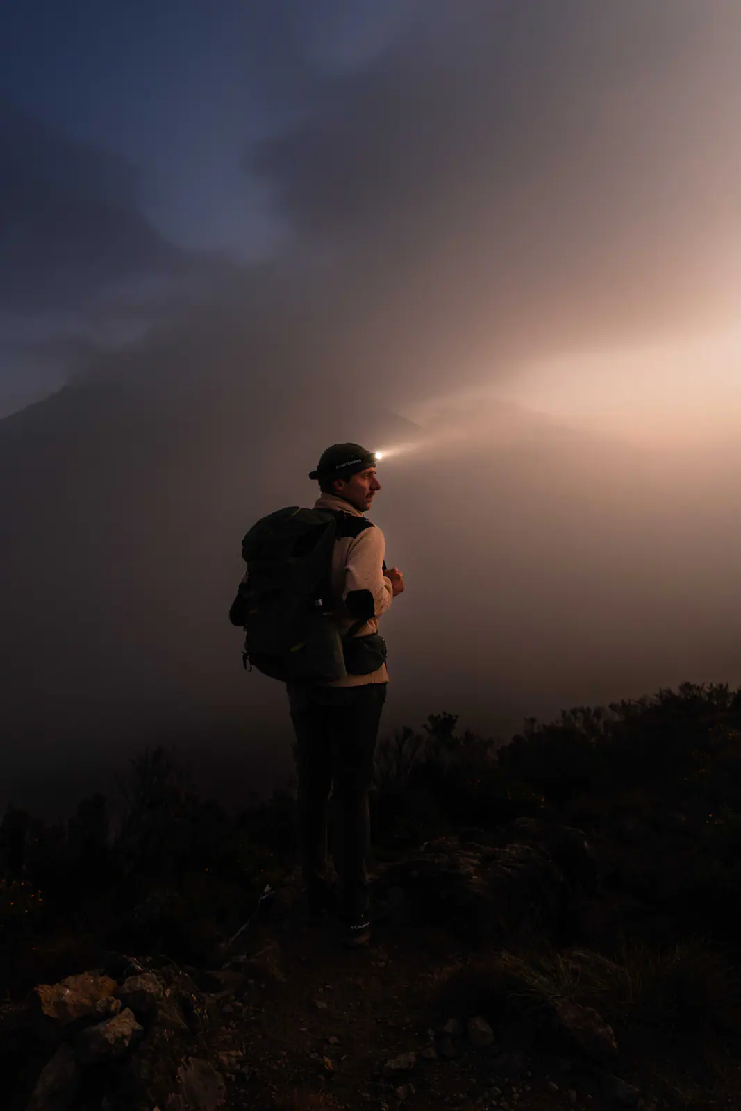 A trekker with a headlamp on the pre-dawn climb