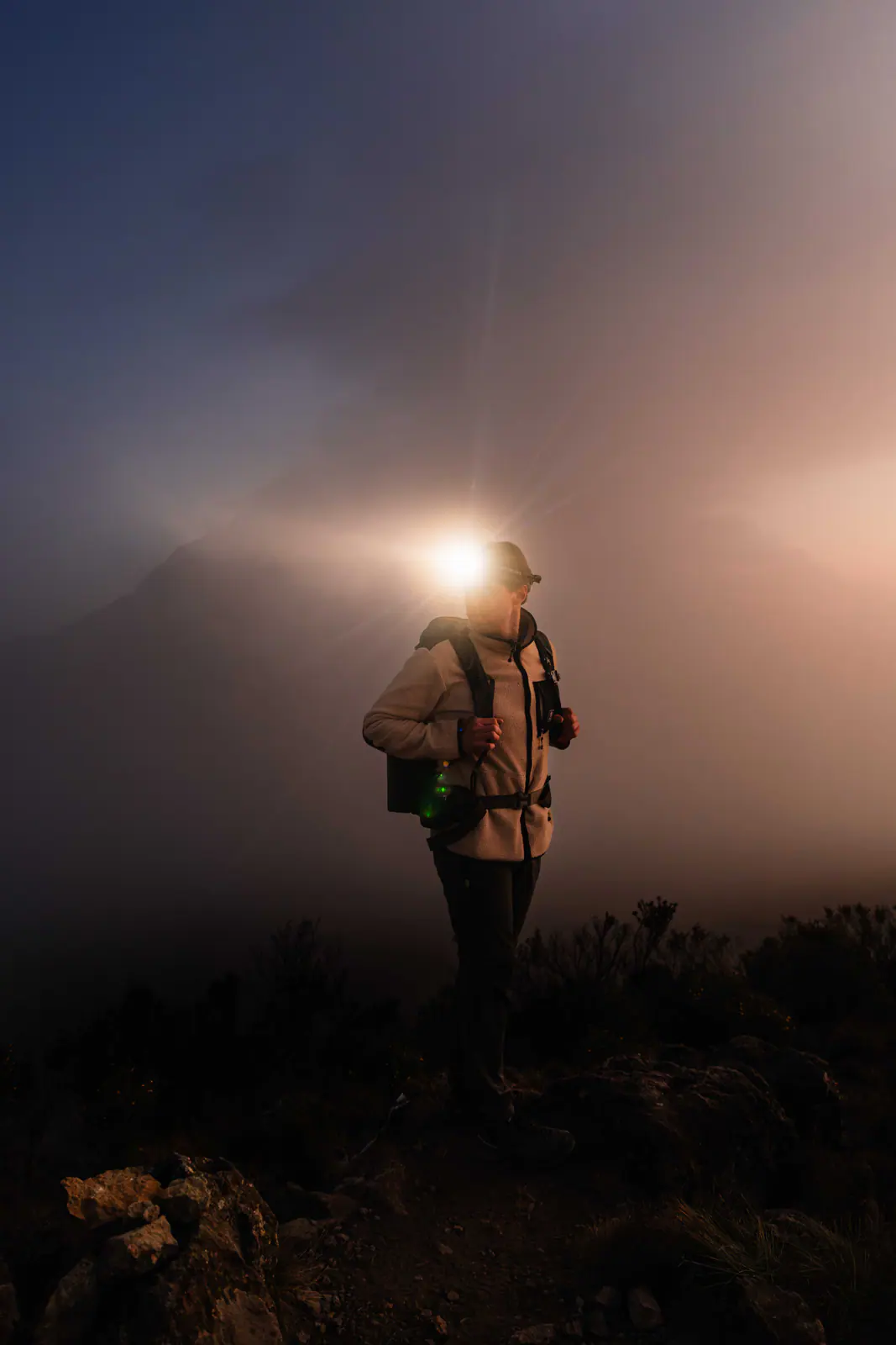 A trekker with a headlamp on the pre-dawn climb