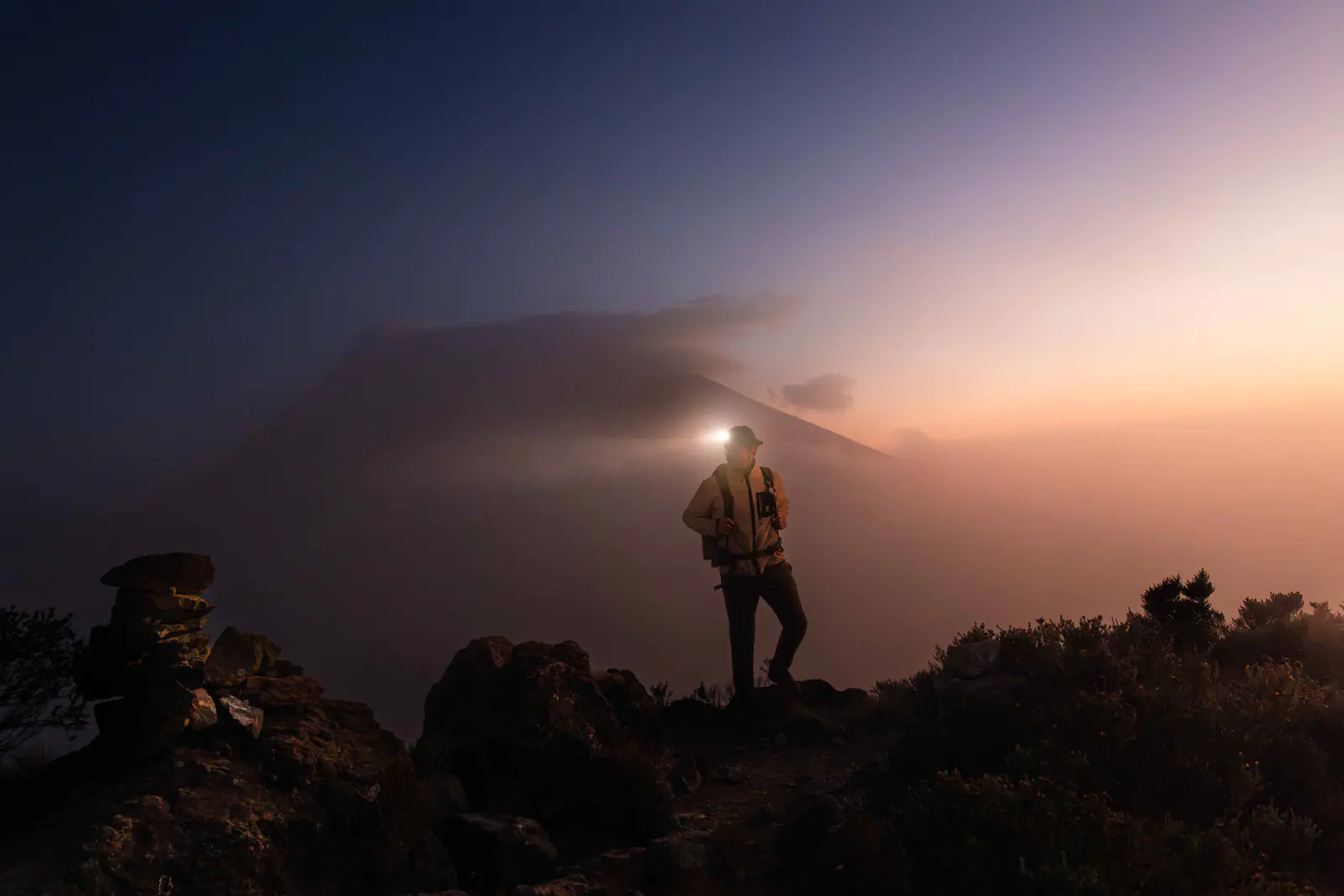 A trekker with a headlamp on the pre-dawn climb