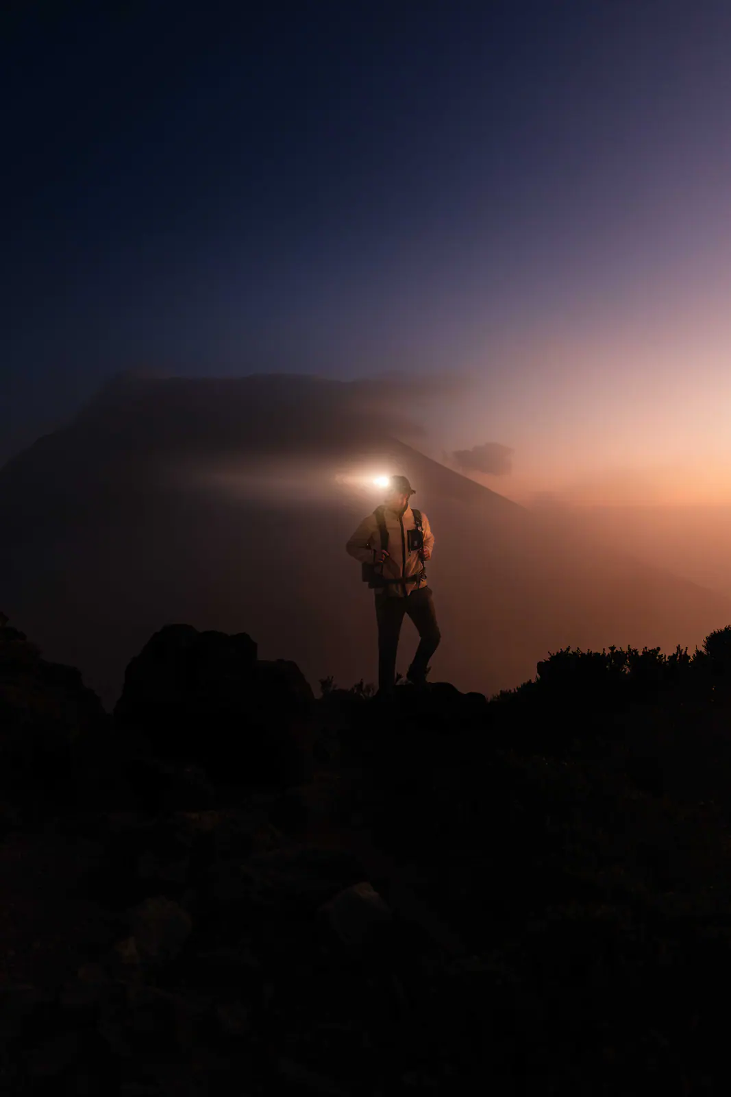 A trekker with a headlamp on the pre-dawn climb