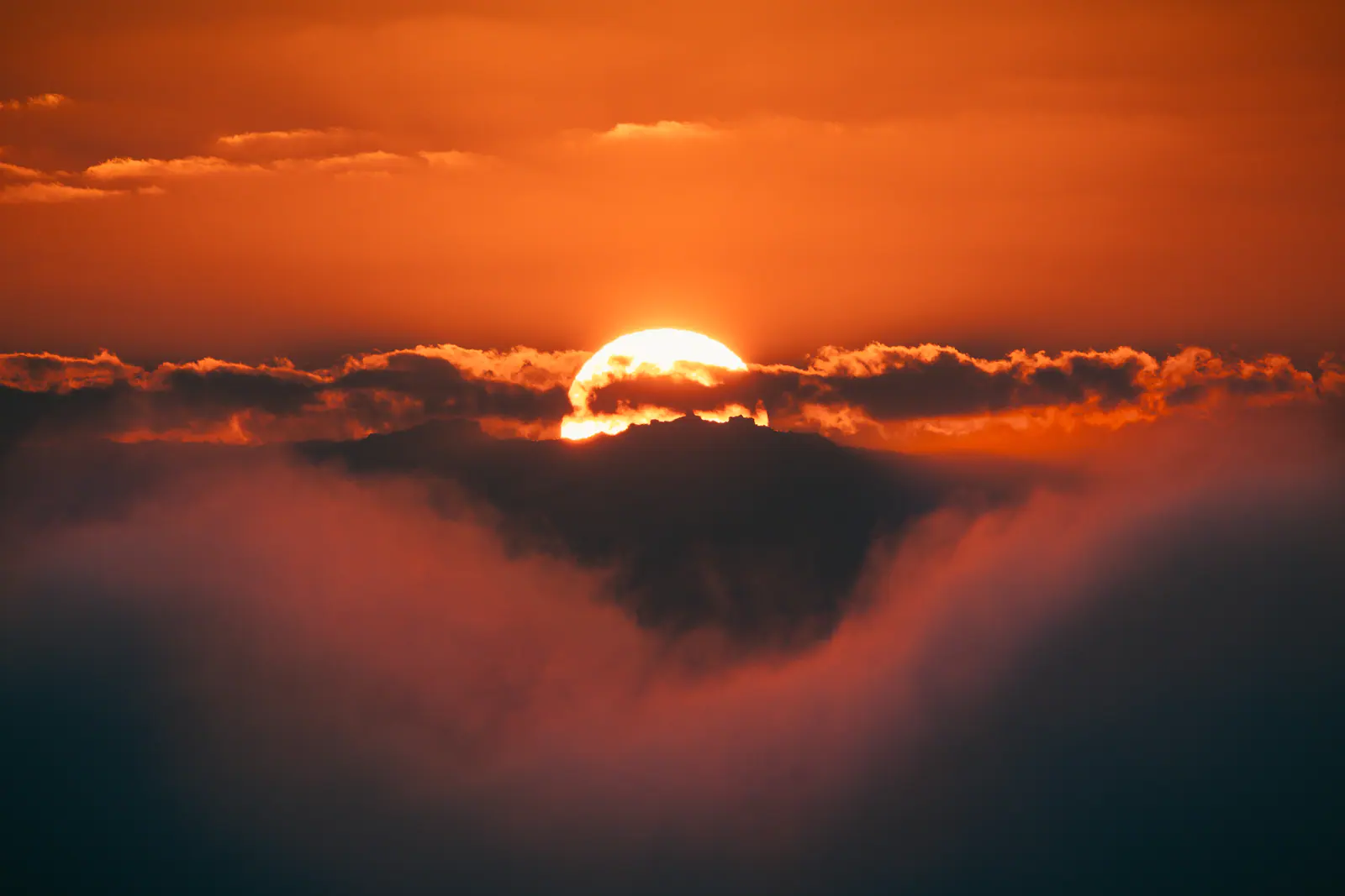 The sun rising through a band of cloud