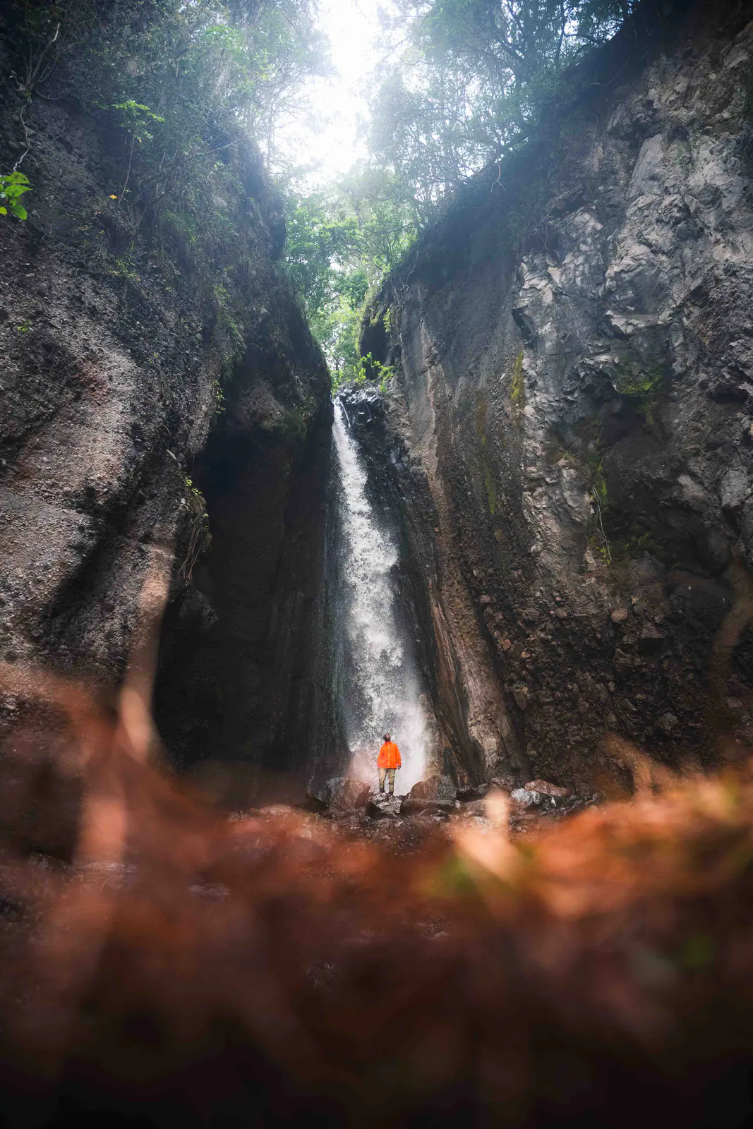 A traveller standing beneath a waterfall