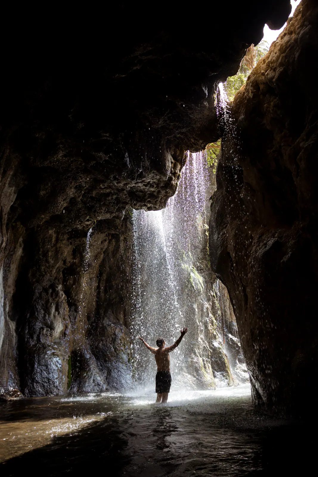 A traveller standing beneath a waterfall